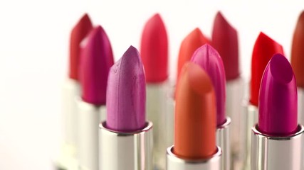 Lipstick tints palette. Fashion colorful lipsticks rotated over white background. Professional makeup and beauty. Lipgloss closeup. 4K UHD video footage. 3840X2160