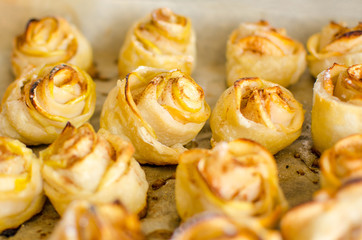 Fresh buns in the form of roses with apples are on the baking tray