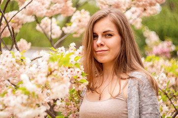 Happy young caucasian woman enjoying cherry blossom in spring