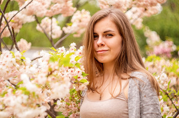 Naklejka premium Happy young caucasian woman enjoying cherry blossom in spring