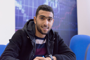 Smiling african american university male student in class  sits at his desk turning to smile at the camera.