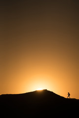 Silhouette of a person running up a mountain