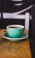 Black coffee in blue cup on wooden background, filter coffee. 