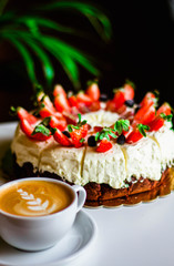 Coffee and brownie with whipped cream and fruits, cup of cappuccino on white table with green background.
