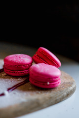French pink macarons on a wooden plate.