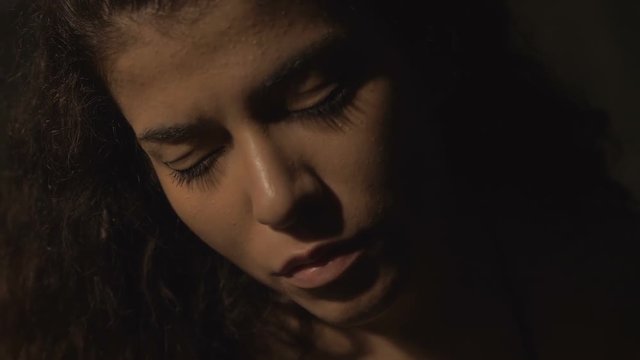 depressed attractive young woman with closed eyes alone in the dark