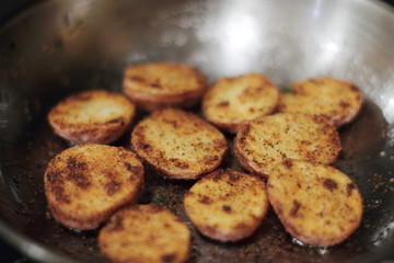 Red potato potato chips cooking in a stainless steel pan.