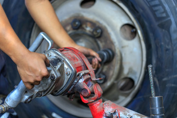 Close up of Truck Wheel mechanic hands using a pneumatic gun to loosen a wheel nut in a mechanical...