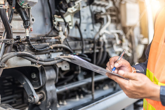 Preforming a pre-trip inspection on a truck,Concept preventive maintenance truck checklist,Truck driver holding clipboard with checking of truck,spot focus.
