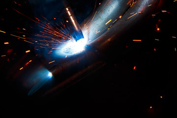 Arc welding. Welding of two metal plates in inert gases. MIG / MAG. A bright flash of light and a sheaf of sparks.