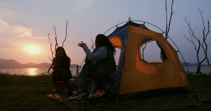 Group of young women enjoy for mini camping near the sea in summer lake together. twilight time sky has clouds. camping, travel and friendship Concept.