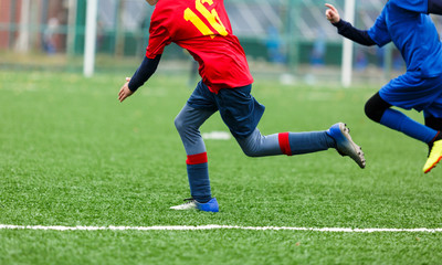 Obraz na płótnie Canvas Football training for kids. Boys in blue red sportswear on soccer field. Young footballers dribble and kick ball in game. Training, active lifestyle, sport, children activity concept 