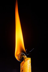 Burning candle close-up, on a dark background.