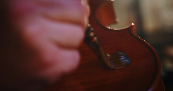 Slow motion macro of professional master artisan luthier  painting a handmade violin in a workshop. Shot in 8K. Concept of spiritual instrument, handmade, art, orchestra, artisan, passion for music
