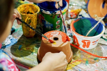 Asian little girl study and learning paint on flower pot in the art classroom of her school.
