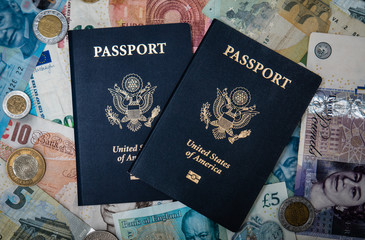 Naklejka premium Two USA Passports with a backdrop of foreign currency meant to illustrate international, exotic, or romantic travel around the world