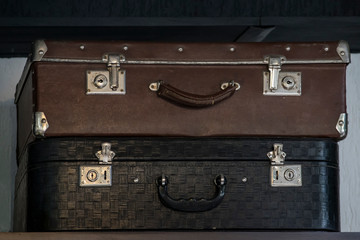 two old suitcases are on the shelf