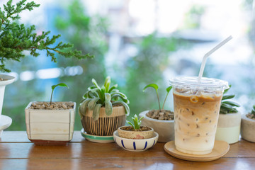 ice latte coffee with green nature on wooden table in garden cafe.