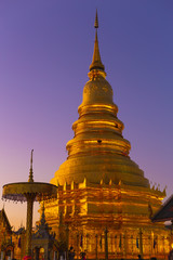 Wat Phra That Hariphunchai Buddhist temple gold pagoda in Lamphun beautiful twilight sky.