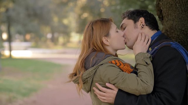 Romantic young lovers kissing under a tree in a park.Attraction,love,romance