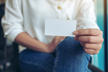 A woman holding and showing a blank empty business card to someone