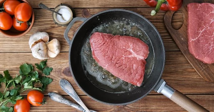 Cinemagraph - Cooking steak in a frying pan. Top view.  Motion Photo. 