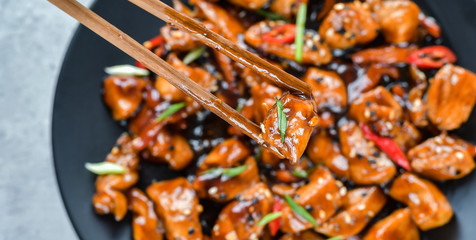 teriyaki chicken's  with  sesame seeds. spicy chicken in sweet and sour sauce with chili pepper. Chinese cuisine, copy space, recipe background, food flat lay, menu of japanese restaurant