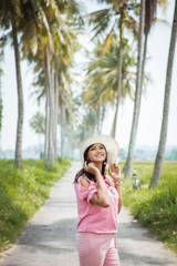 Fototapeta premium asian woman portrait in the summer day. happy enjoy carefree female outdoor with tropical coconut trees