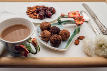 Homemade dates chocolate candy, dried fruits and nuts, and cup of coffee with milk