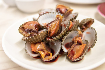Cooked cockle on white plate usually serve with spicy seafood sauce, menu from sea shell. Semi - cooked raw food. 
