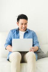Asian man using laptop at home, lifestyle concept with copy space.