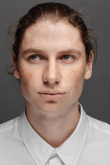 Fototapeta premium Portrait of a handsome long-haired man with drawn hair and freckles dressed in a white shirt