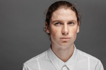 Obraz premium Portrait of a handsome long-haired man with drawn hair and freckles dressed in a white shirt