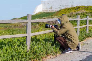 A freelance stock photographer taking picture in a rural setting. Photography in Cape Roca, Portugal.