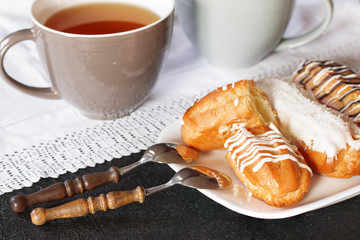 cups of tea and cakes on a plate. dessert in the form of eclairs and a cup of tea.