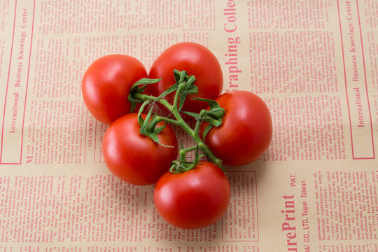 tomatoes on a branch on a newspaper