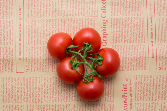 tomatoes on a branch on a newspaper
