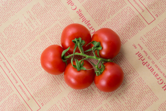 tomatoes on a branch on a newspaper