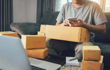 Asian teen men are looking at the phone to find the customer's address in the delivery of the product.