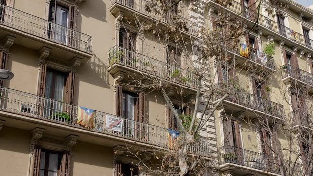 BARCELONA, SPAIN - FEBRUARY 2019. House in Barcelona with balconies on which are the flags of Catalonia and protest posters. The concept of separatism and detachment from Spain in Catalonia. The