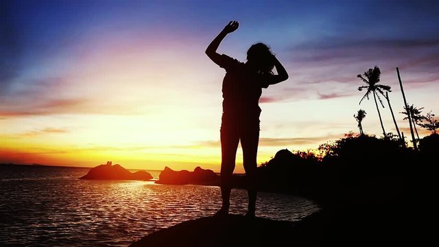 Silhouette of young woman dances at beautiful sunset stands on the rock. slow motion. 1920x1080