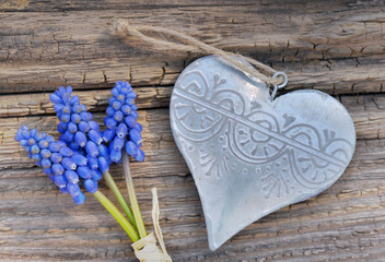 spring blue flowers and  iron heart on a rustic board