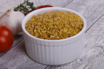 Raw bulgur in the bowl with tomatoes and garlic