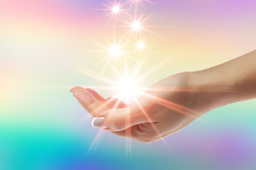 Healing hands with bright sunburst on rainbow background