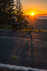 Obraz premium Adventure motorcycle, silhouette touristic motorbike. the mountain peaks in the sunset. Copy space. Concept of Tourism, adventures, active lifestyle, Transfagarasan, Romania, vertical photo