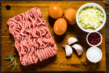 Raw minced pork on cutting board and vegetables