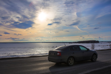 Fototapeta na wymiar car moves along the road along the winter frozen lake