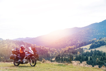 Woman biker with big adventure motorbike, motorcyclists vacation, world traveler, long road trip on two wheels. autumn day. Mountains on background. Romania