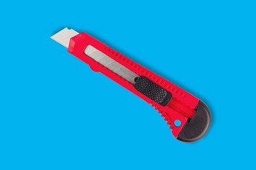 One stationery knife with red plastic handle in center of blue background