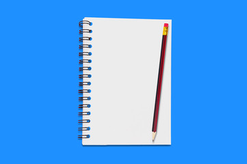One paper notepad with spiral binder and blank sheets near wooden pencil lies of blue office table. Top view. Concept of business or education. Copy space for your text